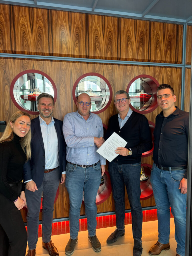 Five executives smile together at the River bar Rotterdam with a signed contact in hand.