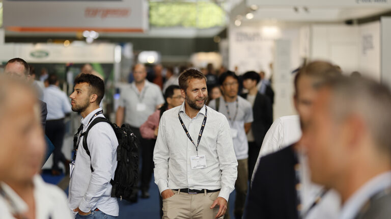 A man walks through a busy expo hall.