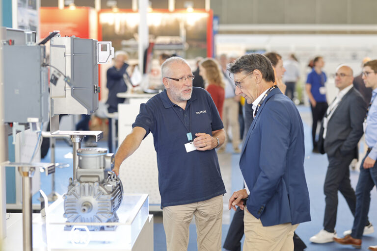 The world’s leading electric and hybrid marine technology trade fair opens in five weeks! Two men discuss a piece of marine technology.