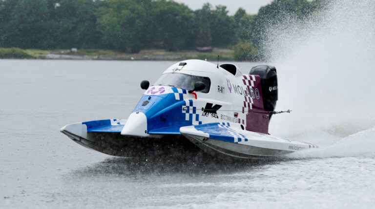 Molabo-powered electric Formula 4 boat hits the water Electric Formula 4 boat racing across an inland waterway at high speed.