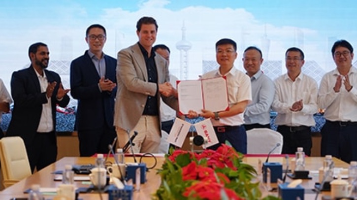 APM Terminals to replace 500 terminal tractors with battery electric models by 2030 Two men shake hands, while holding a signed contract, at a signing ceremony full of clapping men.