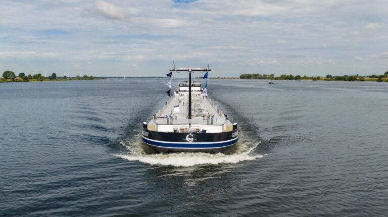 The Mts Generation, a CDS Tanker 110 vessel, sails towwrda the camera on a calm inland waterway with trees on a land in the distance