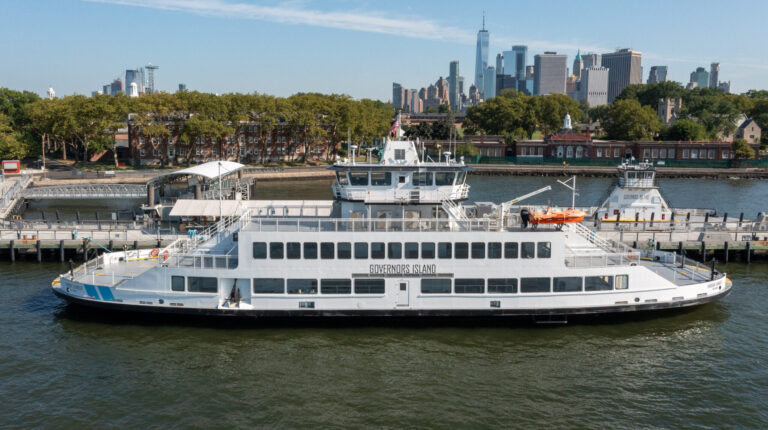 New York State’s first hybrid public ferry, the the Har­bor Charg­er, pictured in service on a sunny day with the New York City skyline visible in the background