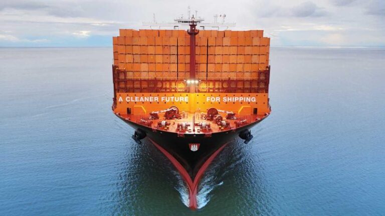 DHL and Hapag-Lloyd announce sustainable maritime fuel partnership A container ship loaded with orange containers sails across a calm sea